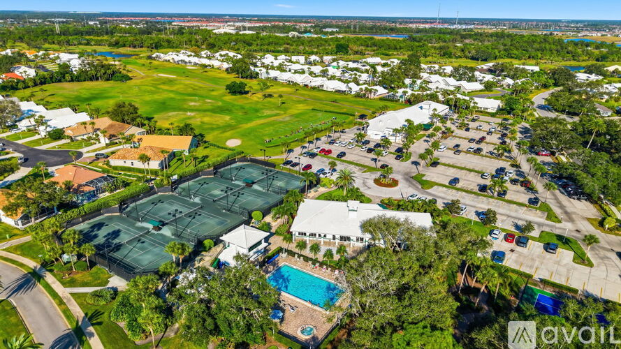 A bird's eye view of a residential area with a swimming pool and tennis courts.