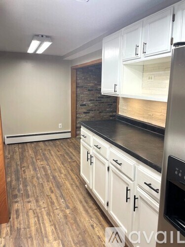 A kitchen with white cabinets and a wooden floor.