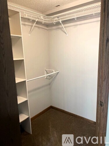 A small, empty room with white shelving and a wooden door.