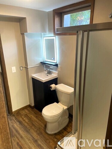A bathroom with a toilet, sink, and mirror.
