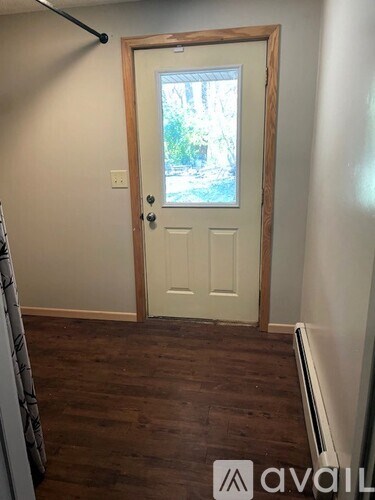 A room with a white door and wooden flooring.