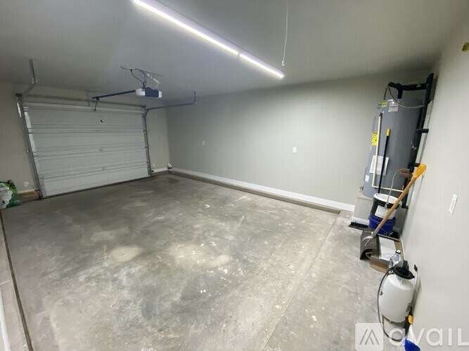 A garage with a concrete floor and a white roller shutter door.