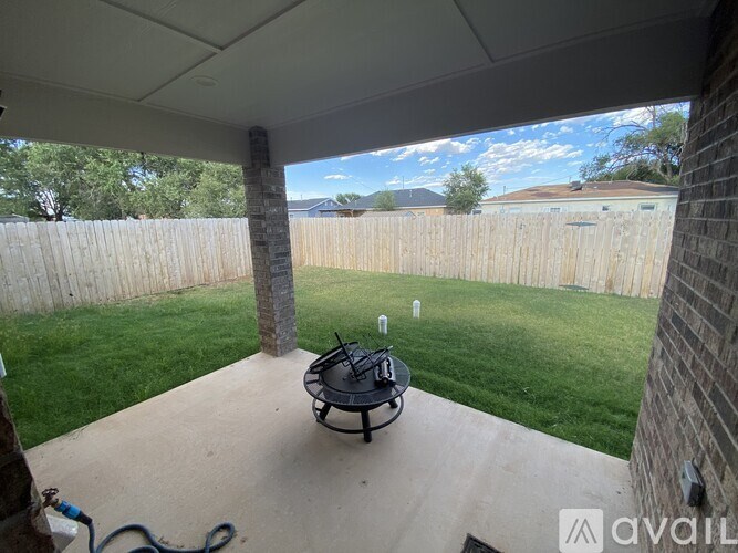 A patio with a table and chairs is covered by a roof.