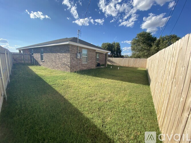 A backyard with a wooden fence and a house in the background.