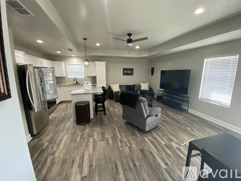 A spacious kitchen and living room with a refrigerator, a dining table, and a couch.
