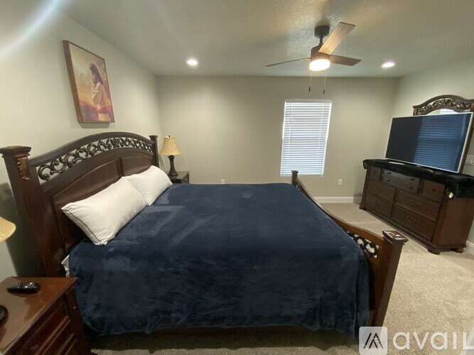 A bedroom with a bed, dresser, and ceiling fan.