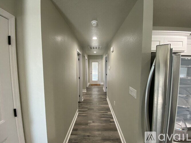 A long hallway with a refrigerator on the right side.