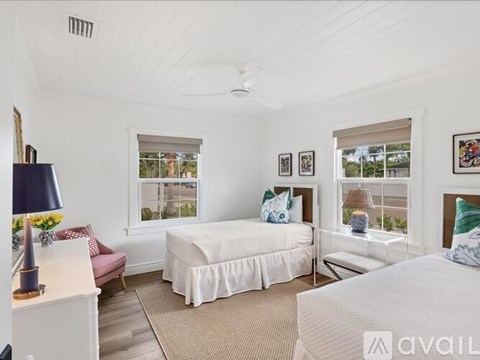 A bedroom with two beds, one with a white bedspread and the other with a blue bedspread.