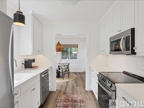 A kitchen with white cabinets and a black fridge.