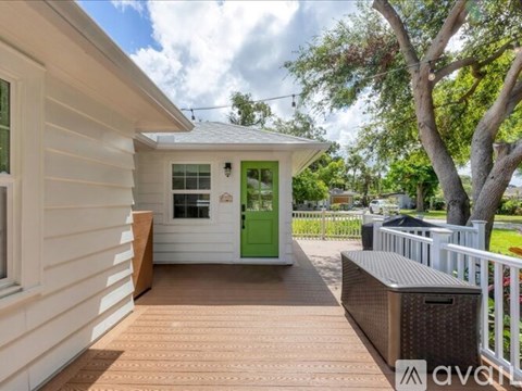 A small white house with a green door and a wooden deck.