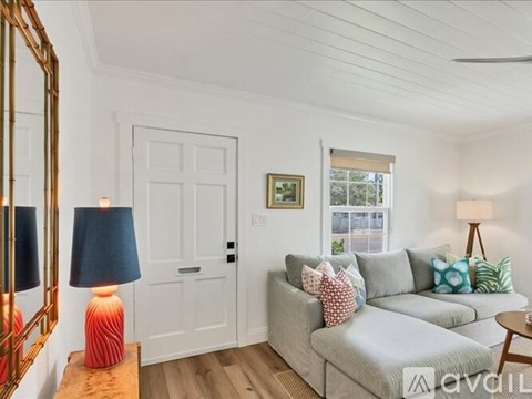 A living room with a grey couch, a wooden table, a lamp, and a painting on the wall.