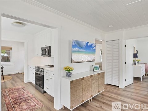 A kitchen with a white cabinet and a painting of a beach scene on the wall.