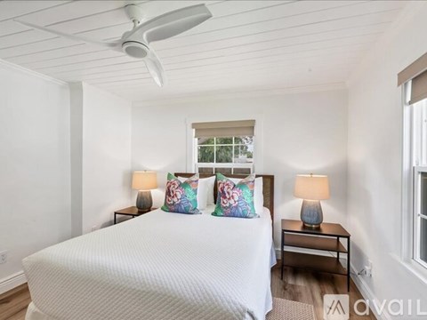 A bedroom with a large bed and two lamps.