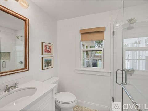 A bathroom with a white toilet, sink, and a window with blinds.