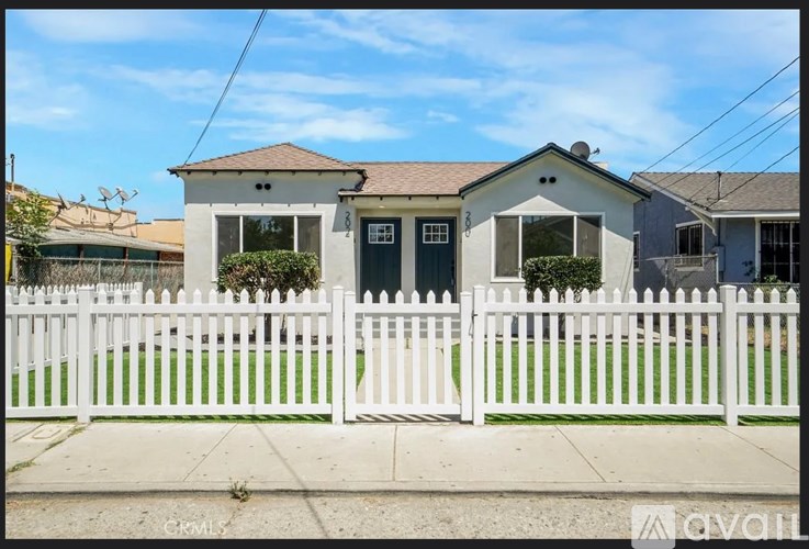 A white picket fence in front of a house.