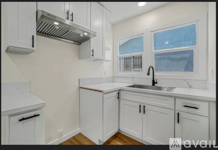A kitchen with white cabinets and a stainless steel range hood.