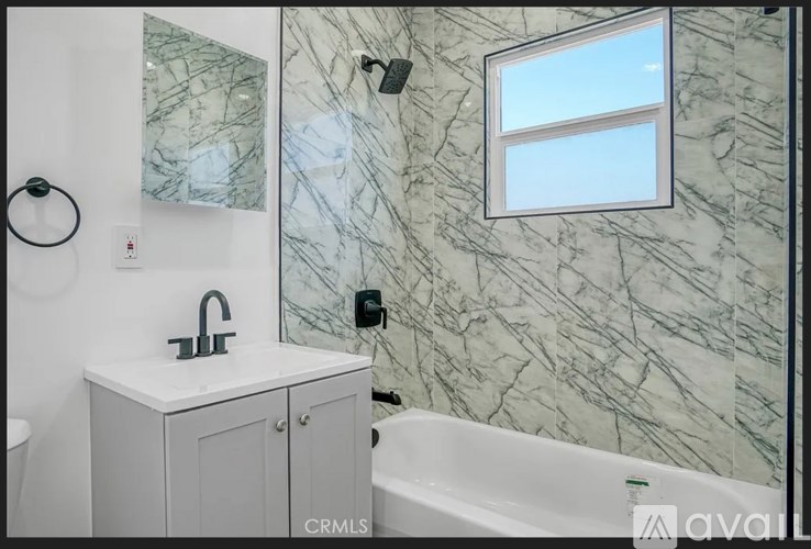 A bathroom with a marble wall and a window.
