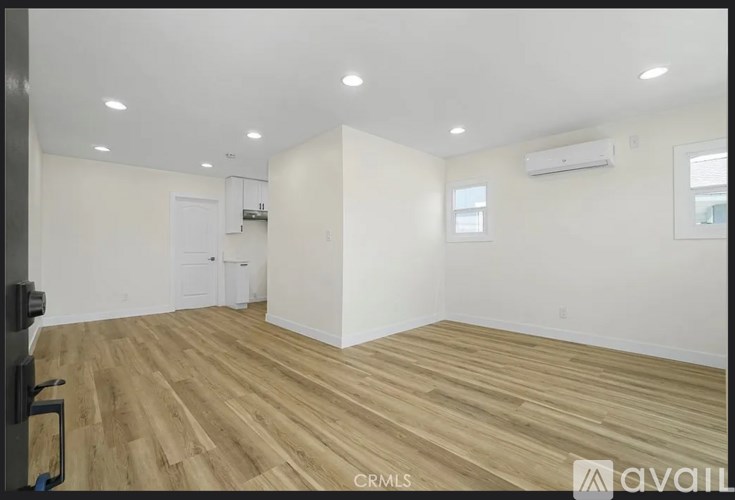 A spacious room with wooden flooring and white walls.