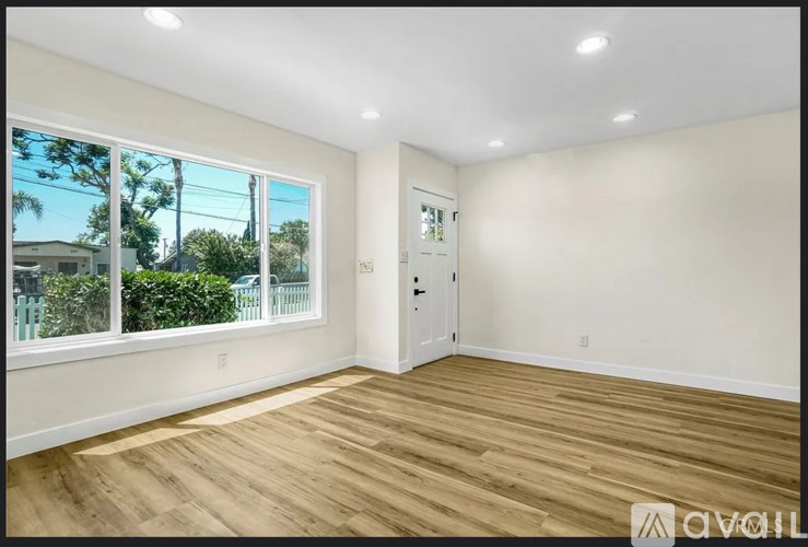 A room with wooden flooring and a door leading to a balcony.