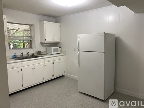 A white kitchen with a fridge, microwave, and cabinets.