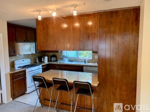 A kitchen with wooden cabinets and a white stove top oven.