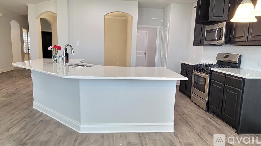A kitchen with a white island and dark cabinets.