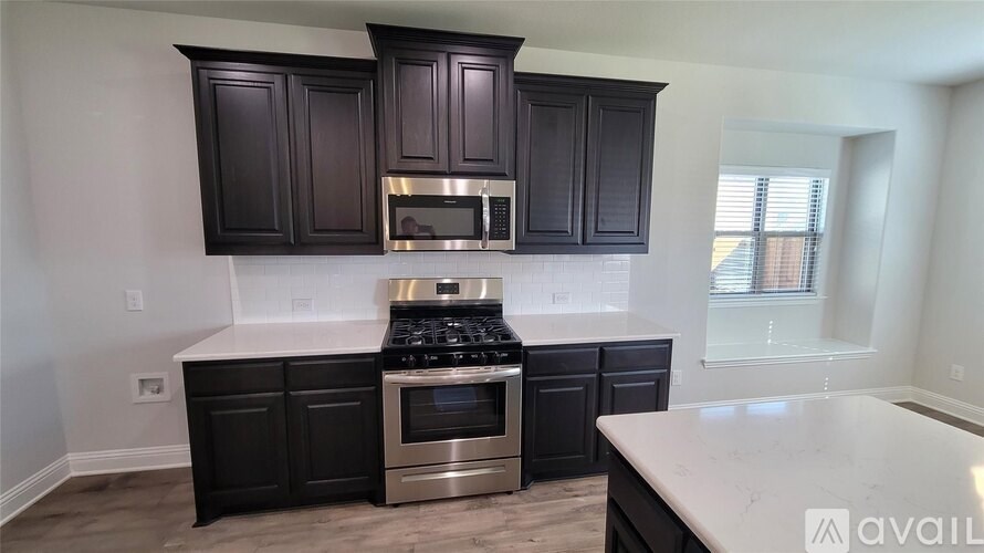 A kitchen with black cabinets and a stainless steel stove top oven.