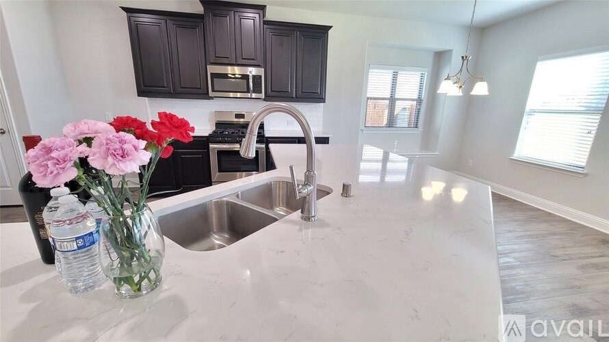 A kitchen with a sink, a microwave, and a counter with flowers on it.