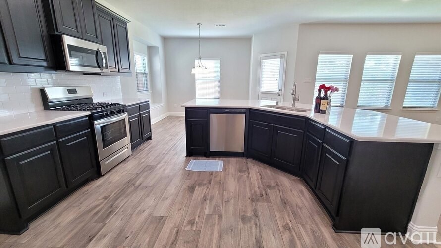 A kitchen with black cabinets and a wooden floor.