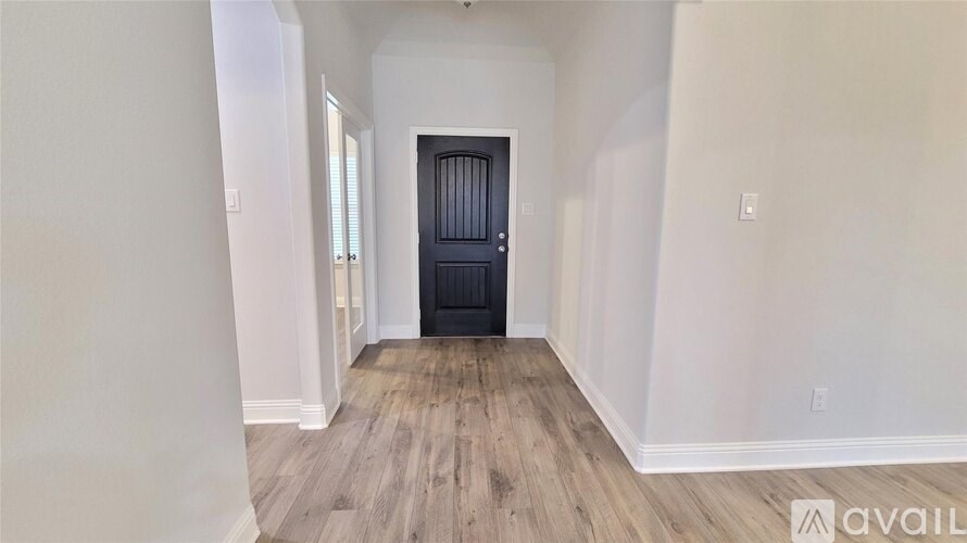 A room with a black door and wooden flooring.