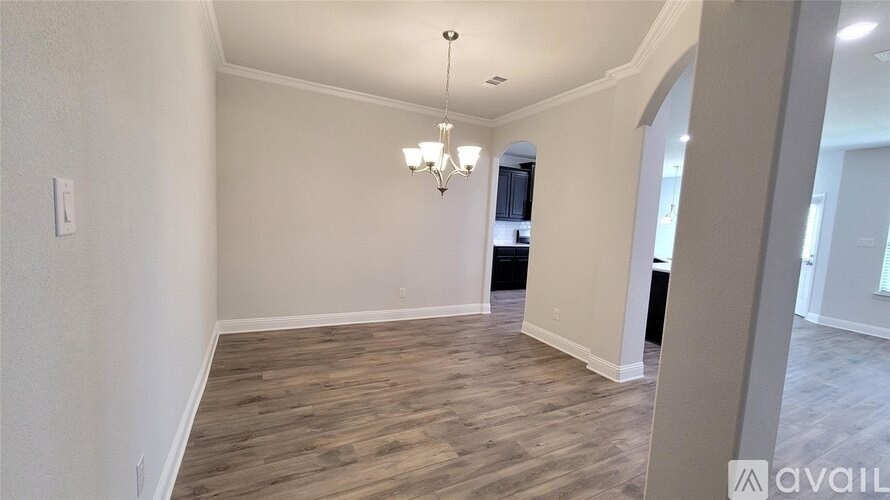 A room with wooden flooring and a chandelier hanging from the ceiling.