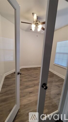 A room with a ceiling fan and a door with a black handle.