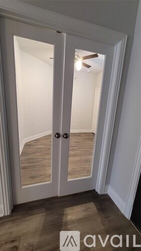 A white door with a glass window and a fan in the room.