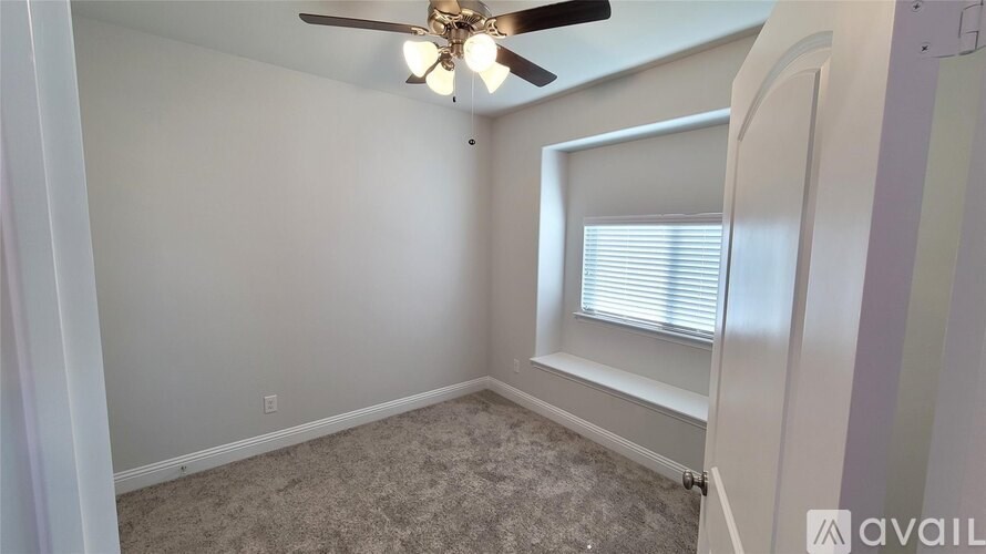 A room with a ceiling fan and a window with blinds.