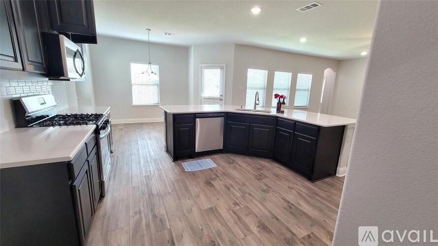 A kitchen with black cabinets and a wooden floor.