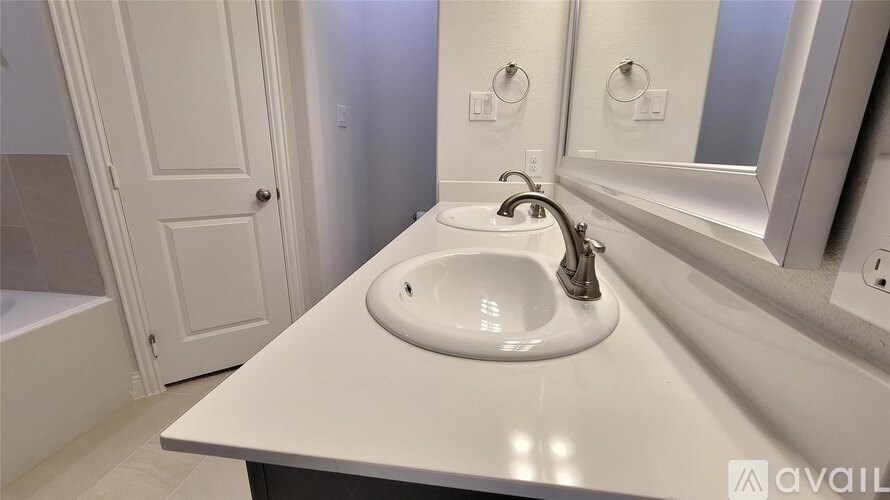 A white sink in a bathroom with a mirror above it.