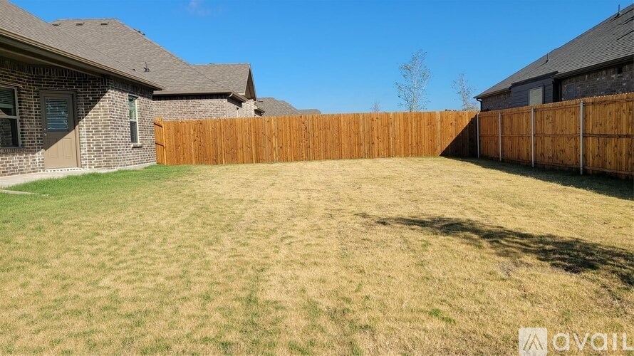 A backyard with a wooden fence and a house in the background.
