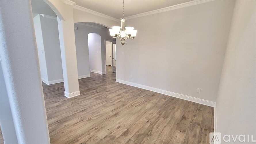 A room with wooden flooring and a chandelier hanging from the ceiling.