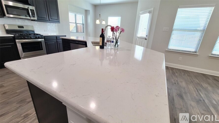 A kitchen island with a marble top and a vase of flowers on it.