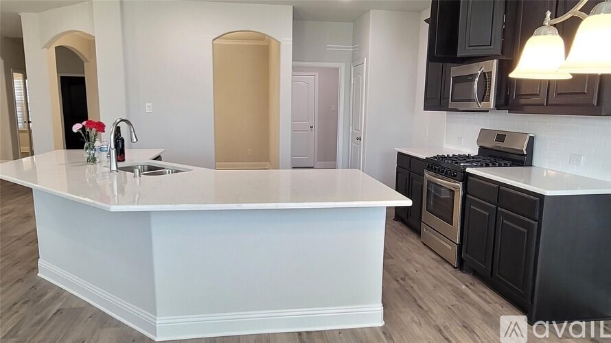 A kitchen with a white island and dark cabinets.