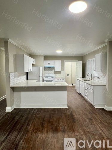 A kitchen with white cabinets and a wooden floor.