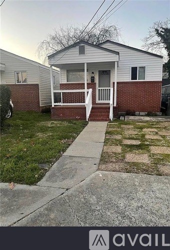 A small house with a porch and a sidewalk in front.