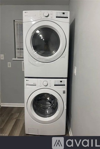 Two white front loading washing machines stacked on top of each other.