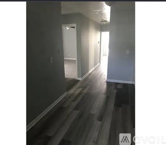 A long hallway with wood floors and a door at the end.