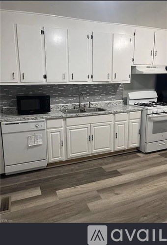 A kitchen with white cabinets and a black microwave.
