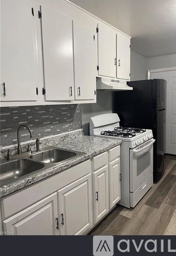 A kitchen with white cabinets and a black refrigerator.