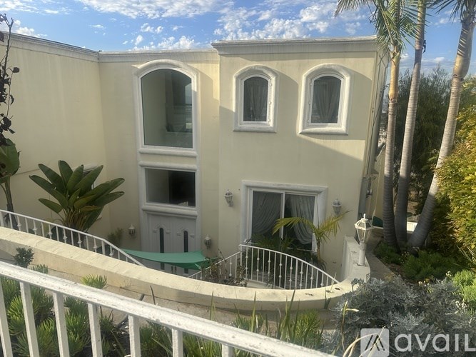 A white building with a balcony and a green awning.