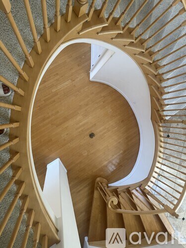 A wooden spiral staircase with a white landing.