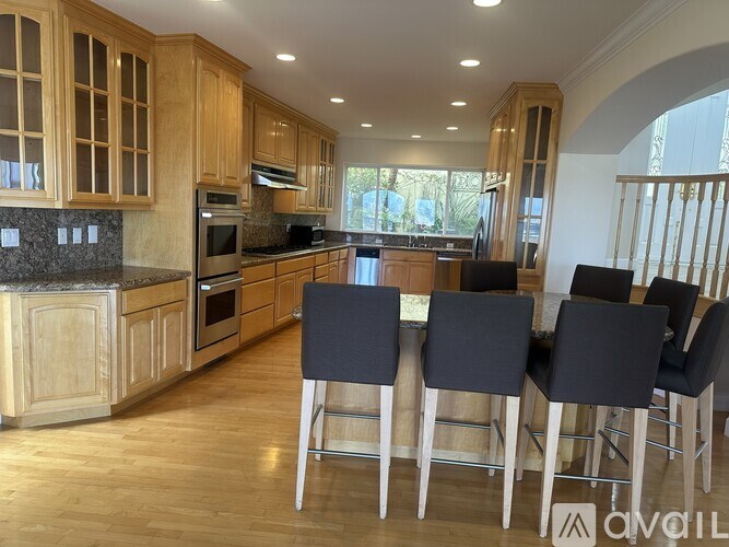 A kitchen with wooden cabinets and a bar area with four chairs.
