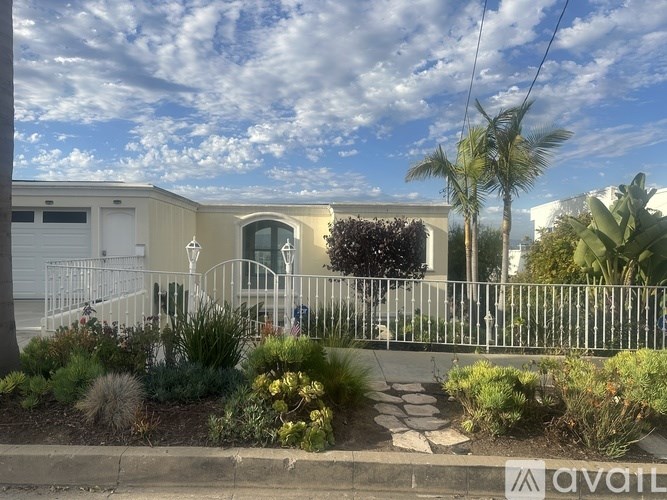 A house with a white fence and a garden in front.